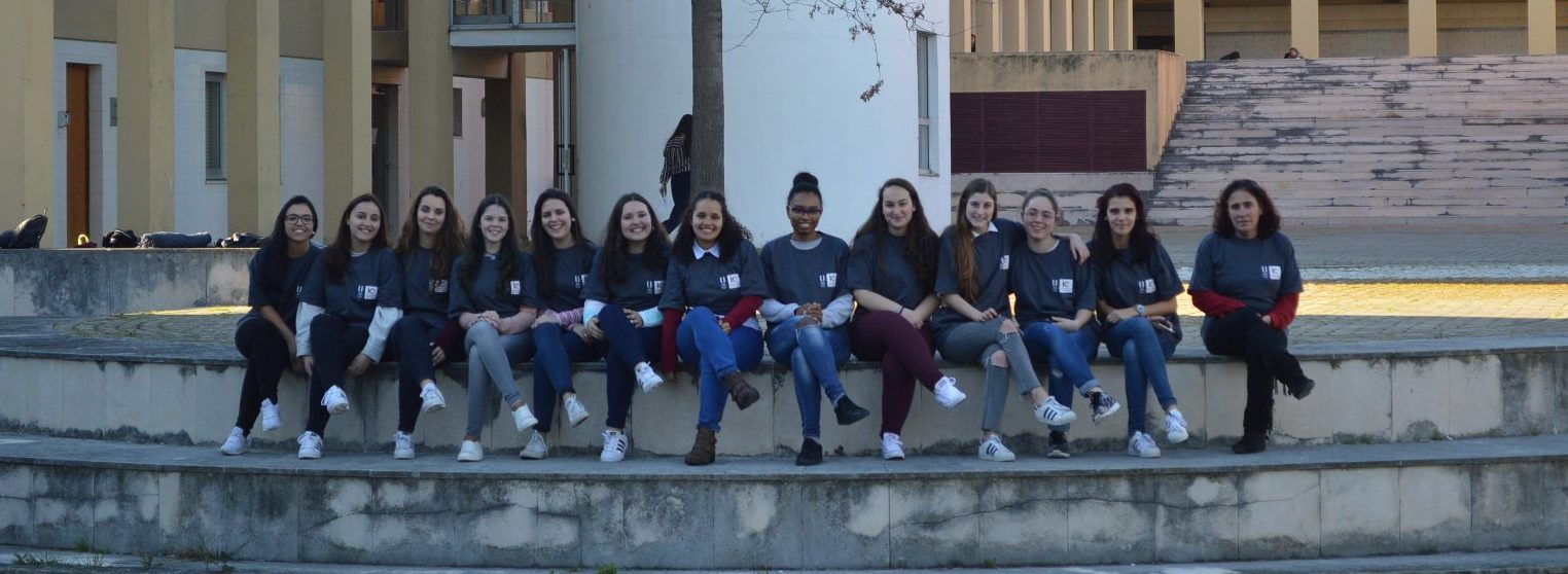 Estudantes Grupo de estudantes do 2.º ano da licenciatura em Educação e Formação, vestidas com a t-shirt do Instituto de Educação, sentadas nas escadas que dão acesso ao lago. Atrás, vista do edifício.
